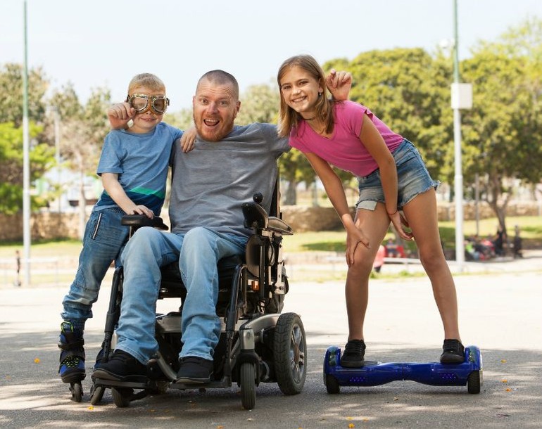 Mann im Rollstuhl mit Kindern im Park